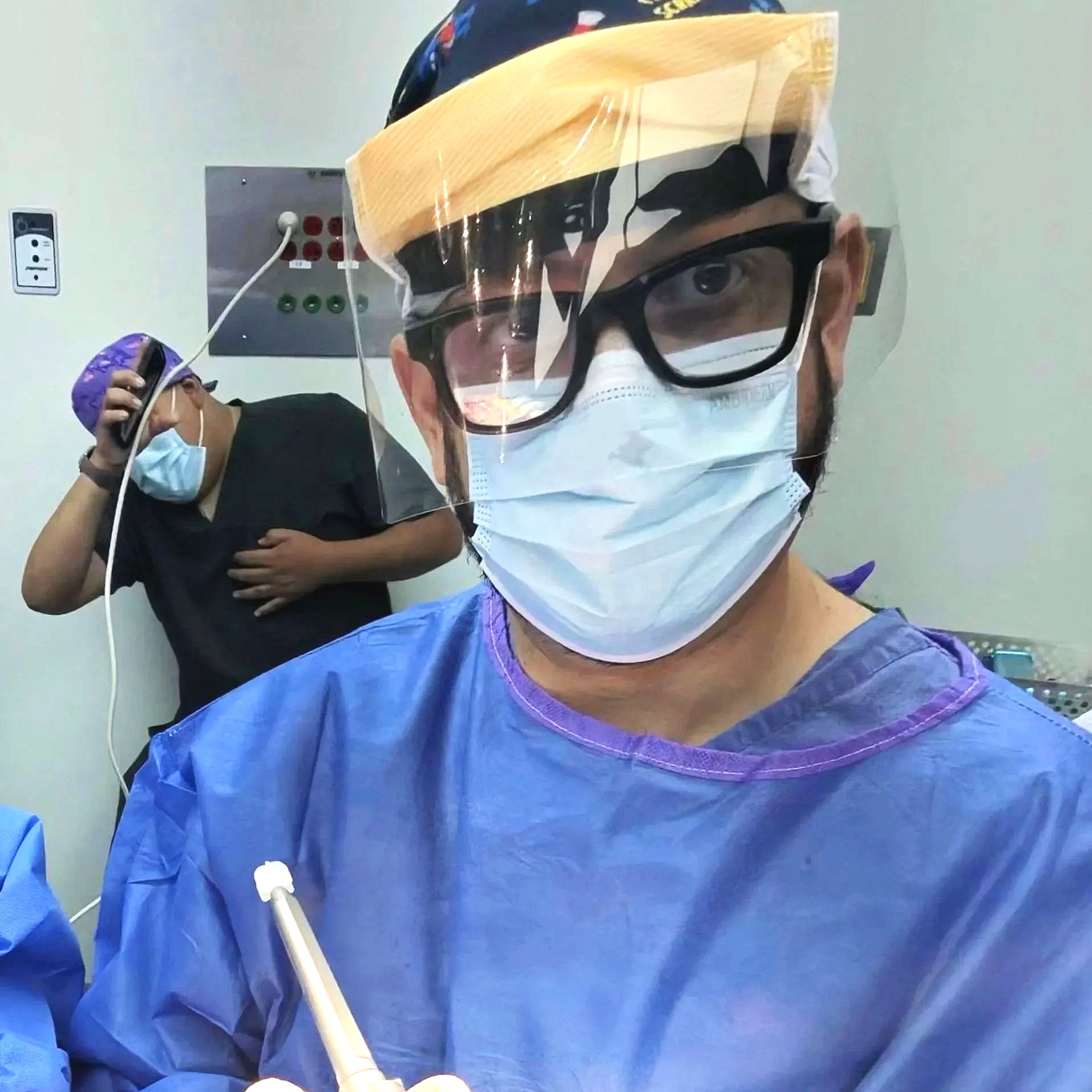 Médico usando equipo de protección, incluyendo mascarilla, gafas, careta y bata, en un entorno hospitalario