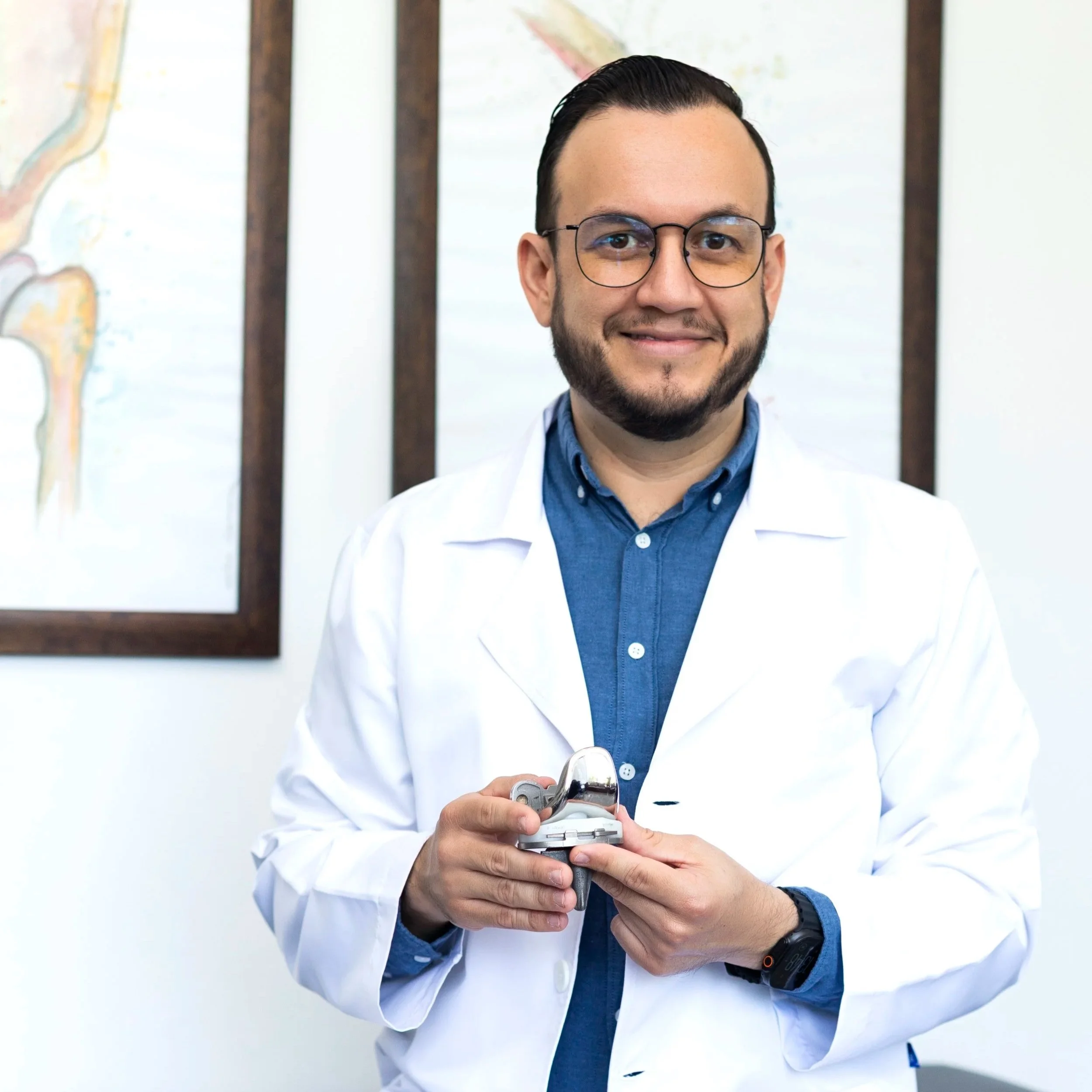 El Dr. Israel Romo  mostrando una prótesis de rodilla en su consultorio