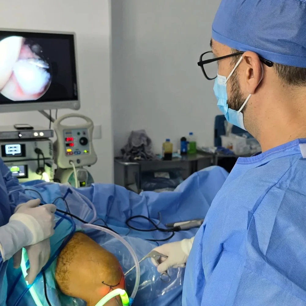 El Dr. Israel Romo durante una artroscopia de rodilla, con la imagen de la cámara en el monitor