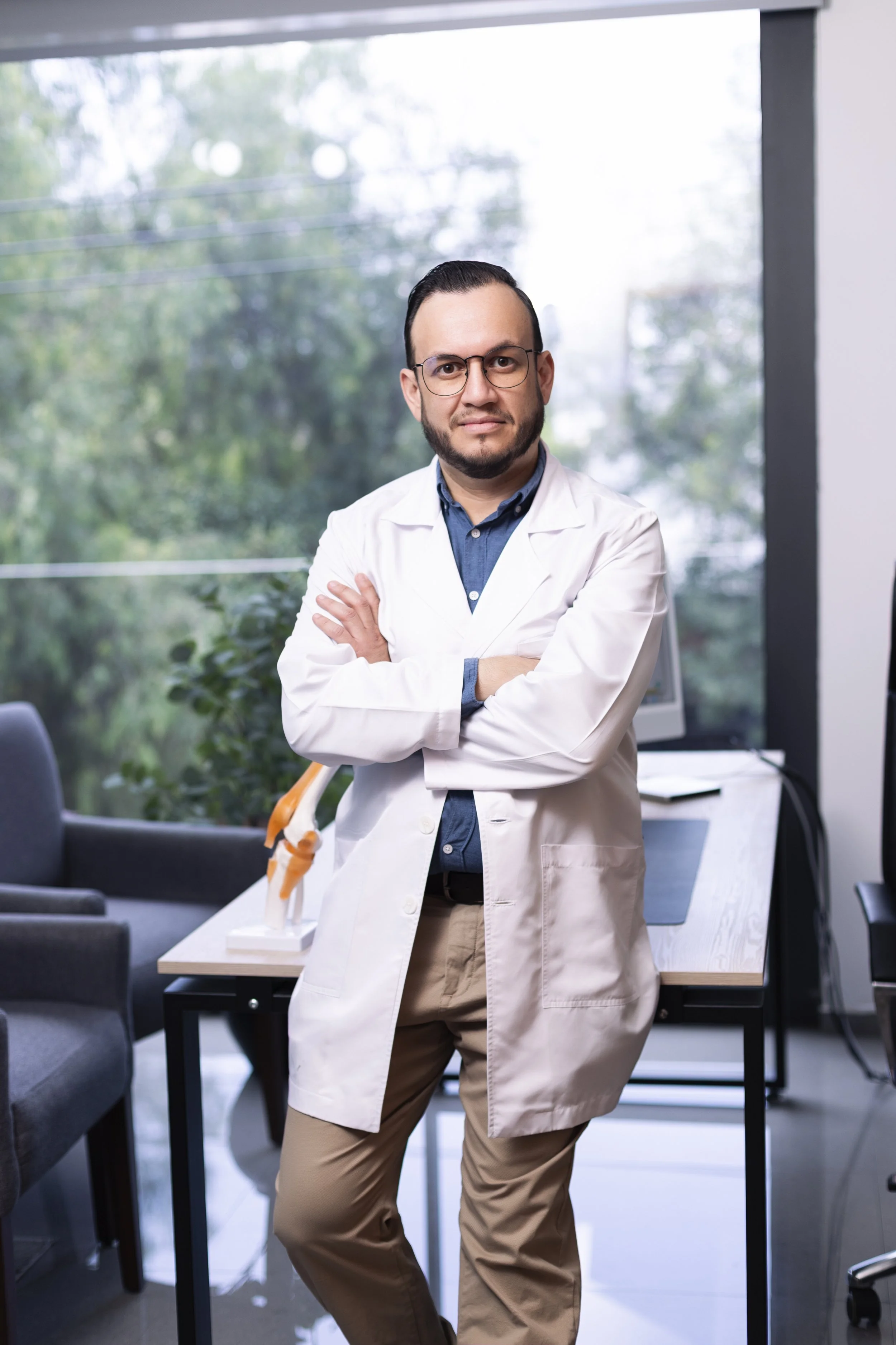 Doctor con bata blanca, brazos cruzados, en consulta médica de ortopedia en Guadalajara