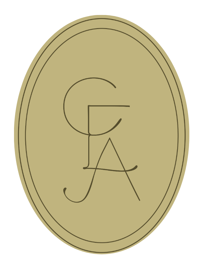 A gold-colored oval coin with the letters G, J, and A engraved on its surface.