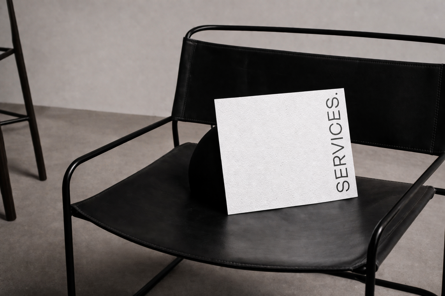Black chair with a white sign reading "SERVICES" leaning against a black curved object on the seat.