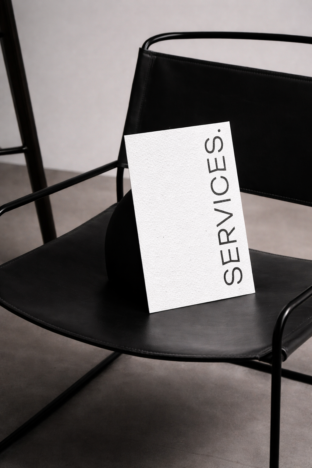 A black chair with a white Serviolies shopping bag resting on it, in a minimalist setting.