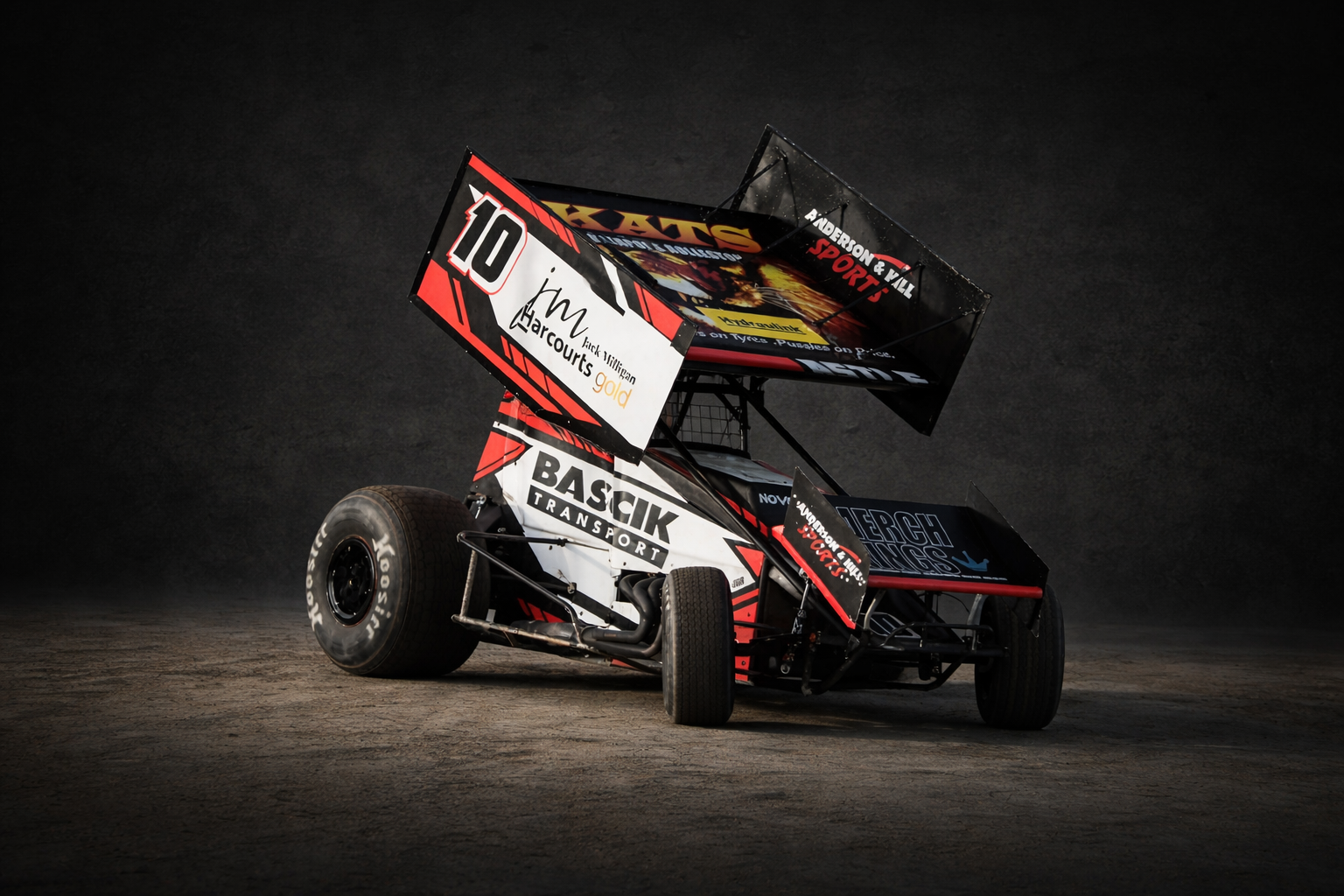 A black and red sprint car with large rear wing and sponsor logos on a dark background.