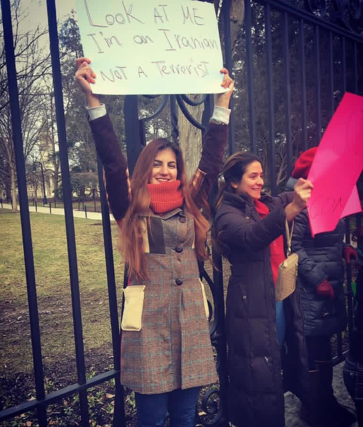 Woman holding a sign that says 'Look at me, I'm an Iranian not a terrorist' during a protest.
