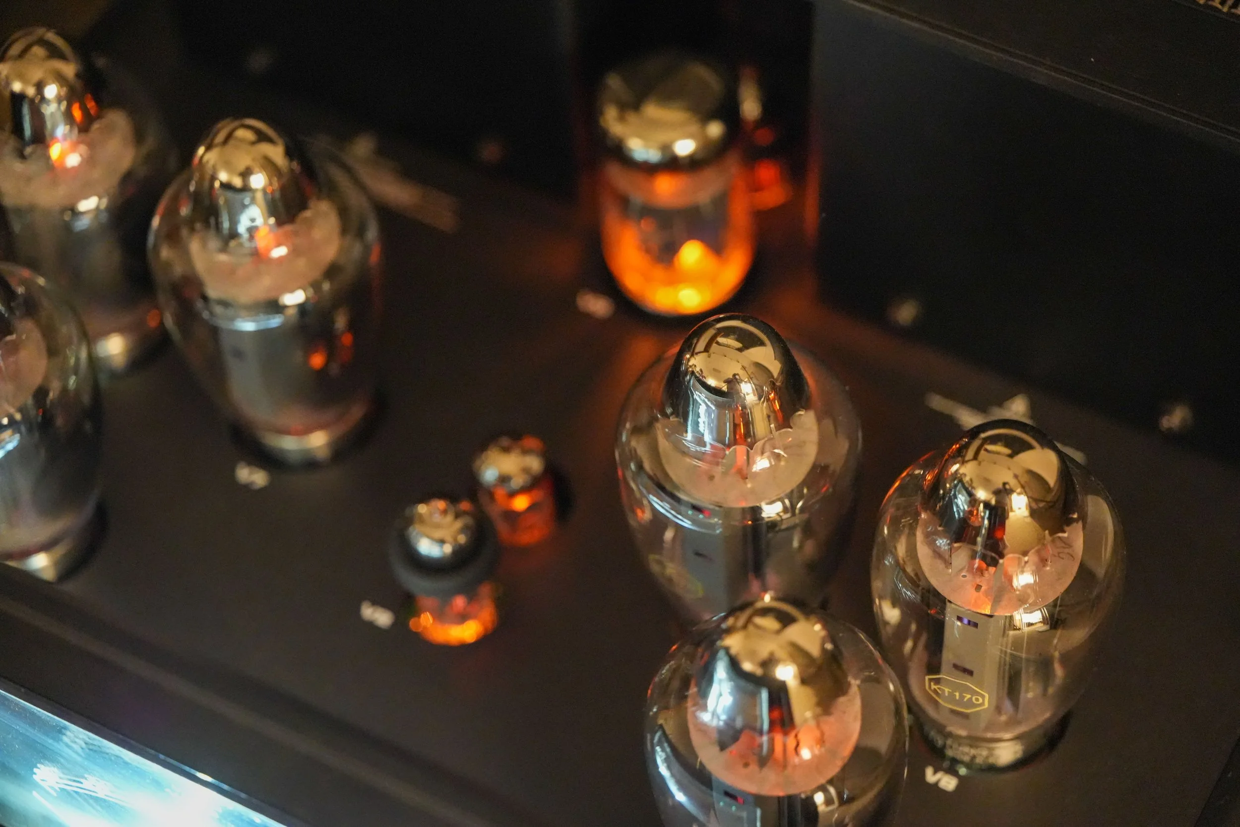 Close-up of vacuum tubes on an audio amplifier, with glowing orange and silver reflective surfaces.