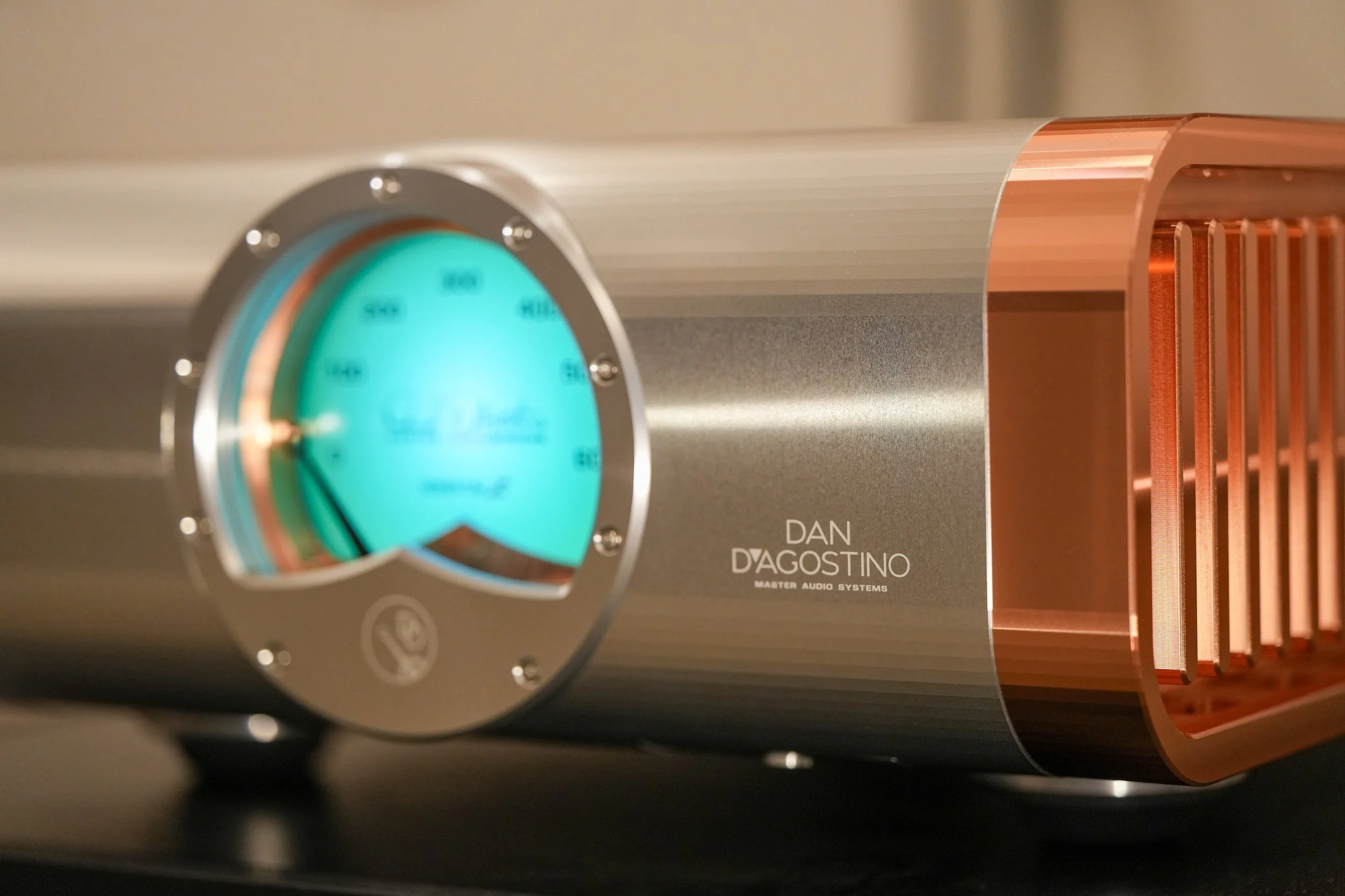 Close-up of a Dan D'Agostino Master Audio Systems audio component, featuring a large, illuminated volume dial and copper heatsinks on the right side.