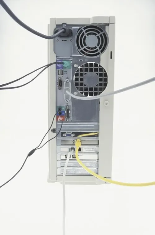 Back of a desktop computer tower with cables connected to various ports.