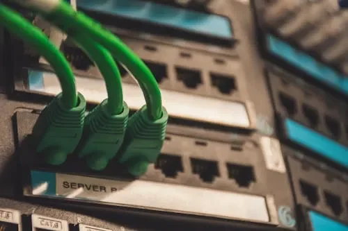 Close-up of three green Ethernet cables connected to a network switch or server rack.
