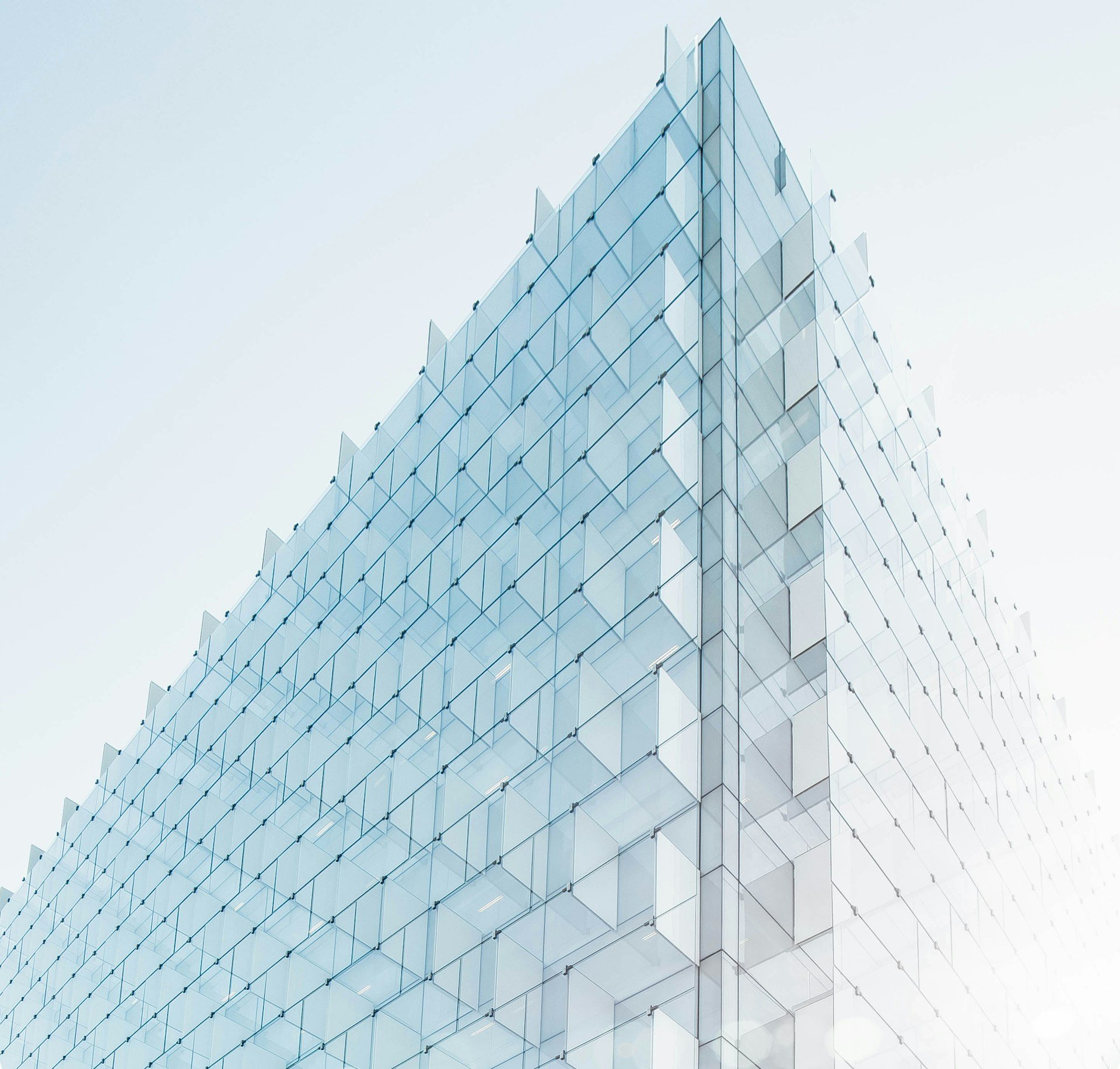 Close-up of a modern glass building with sharp, angular design and reflective glass panels.