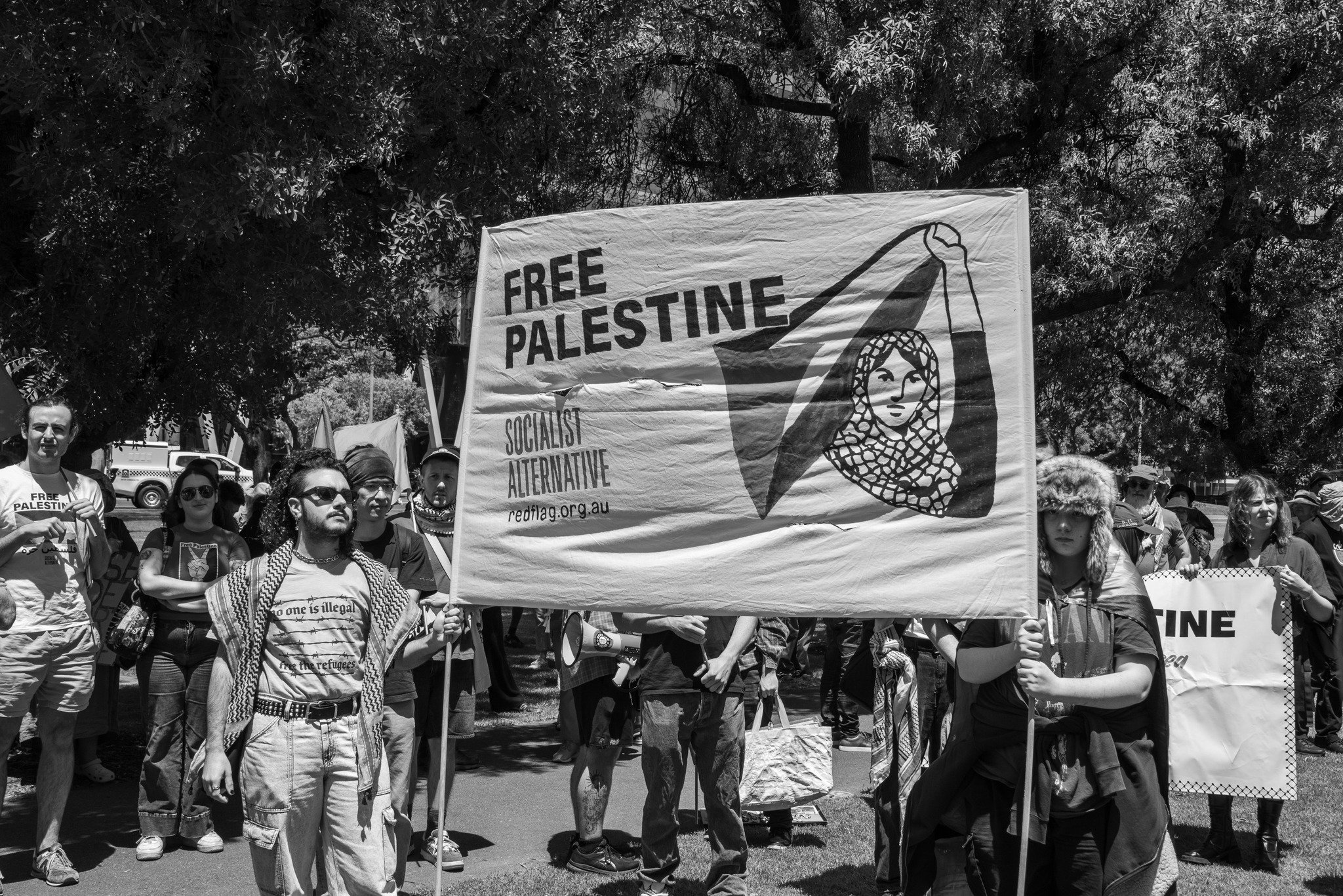 A group of people participating in a protest or march, holding a large banner with the text "Free Palestine".  Image taken by Vicky Dennison.