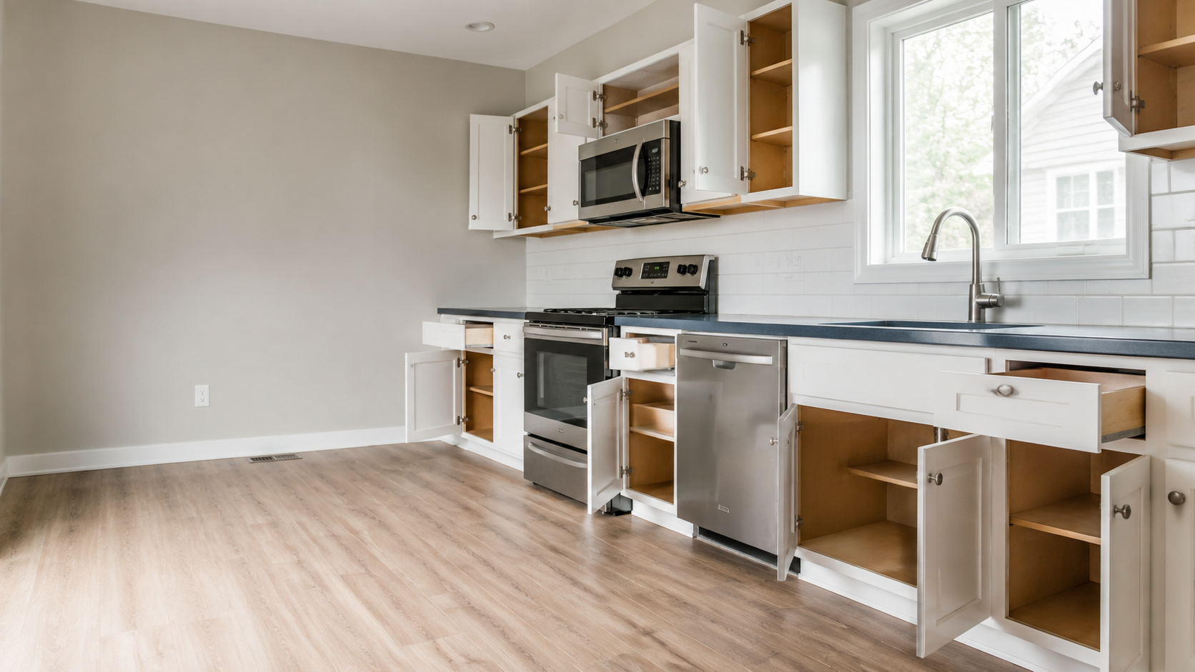 Empty move-ready kitchen with freshly cleaned cabinet and drawer interiors, counters, appliances, and floors.