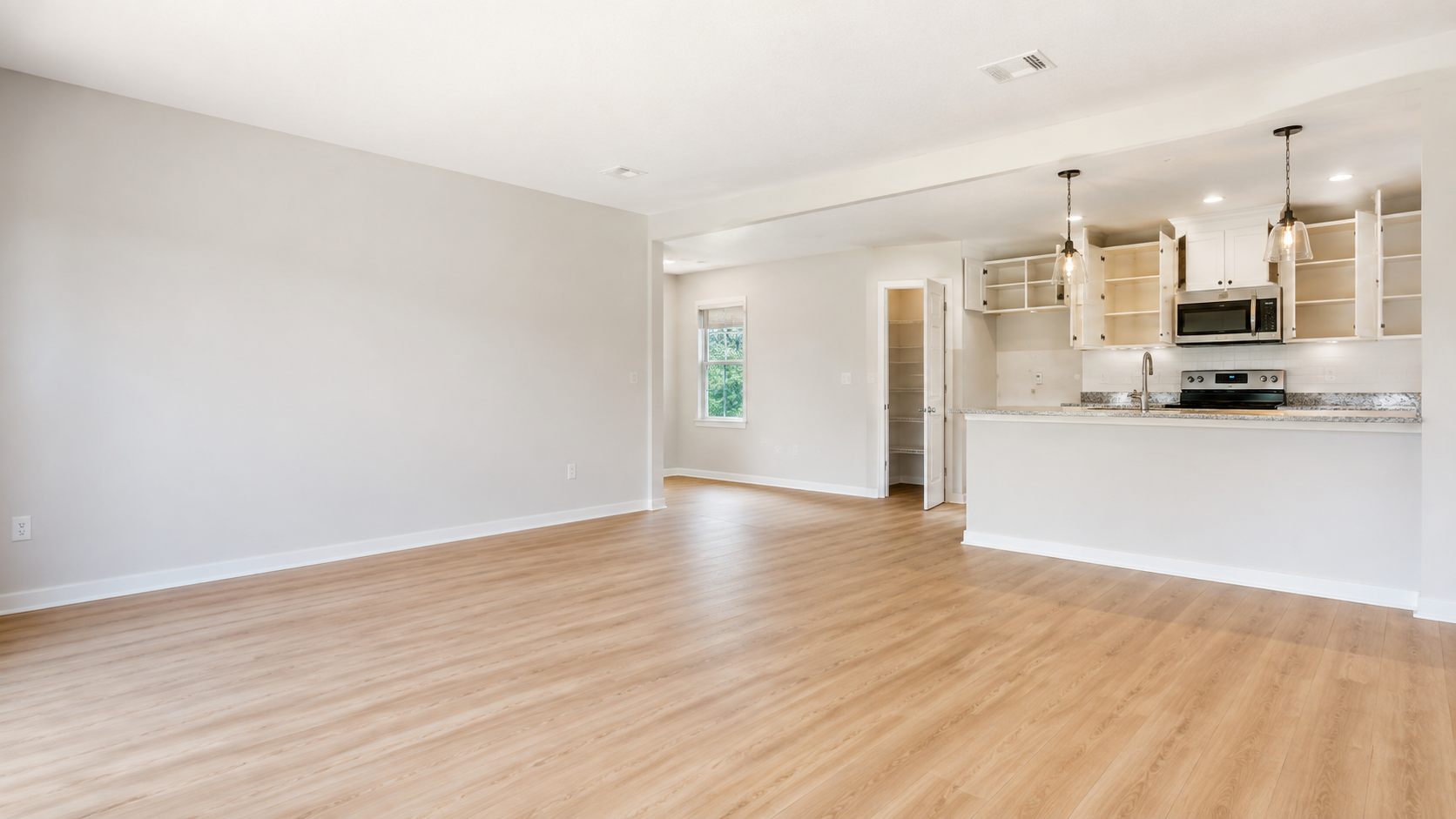 Bright empty home with clean floors, baseboards, kitchen surfaces, and empty cabinets ready for move-in.