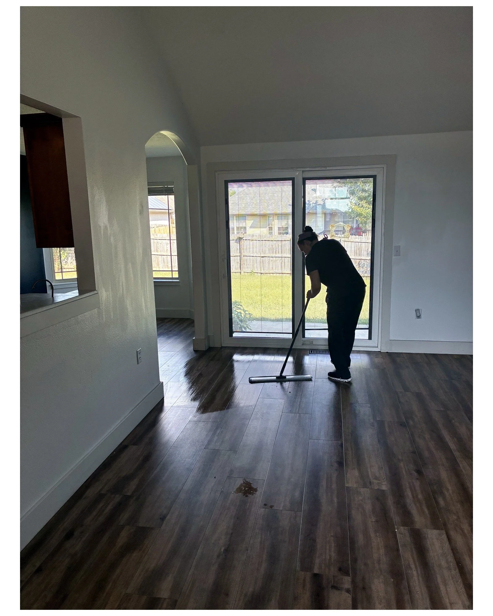 Cleaner mopping a wood-look floor inside an empty home