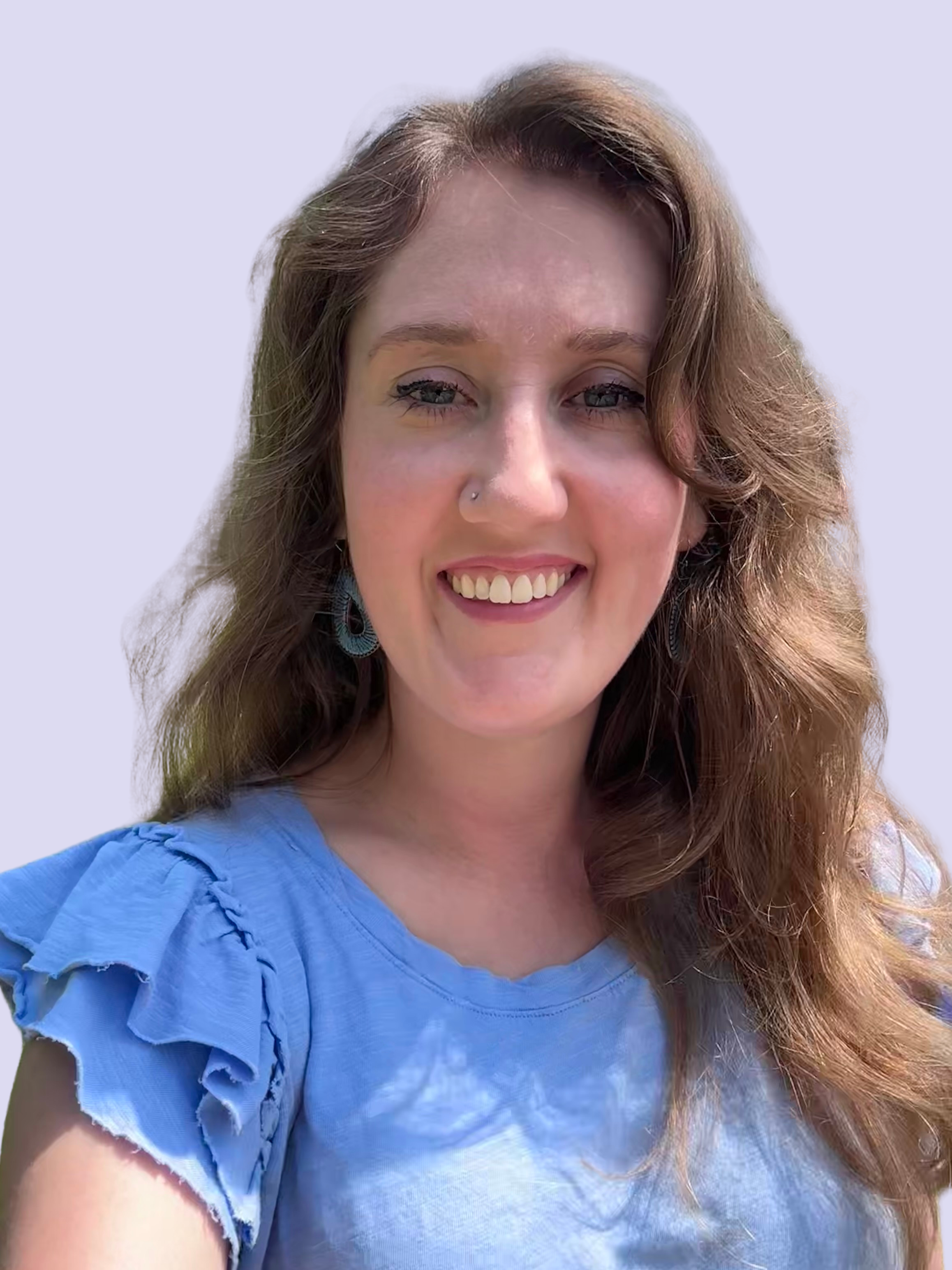 A woman with long, wavy reddish-brown hair, blue eyes, wearing a light blue blouse with ruffled sleeves and earrings, smiling, against a plain light background.