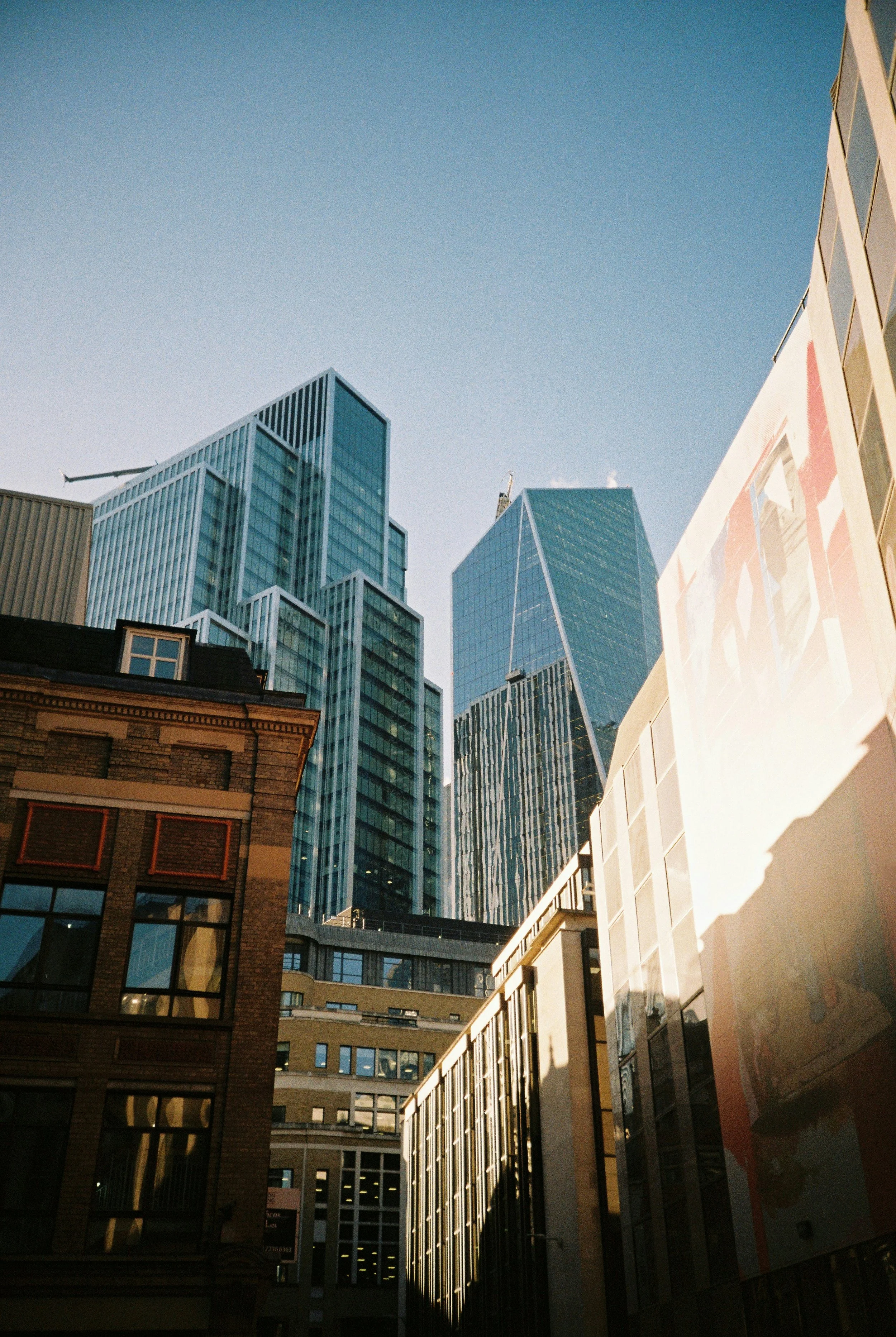 Skyscrapers and city buildings in downtown with clear blue sky, sunlight illuminating the buildings.
