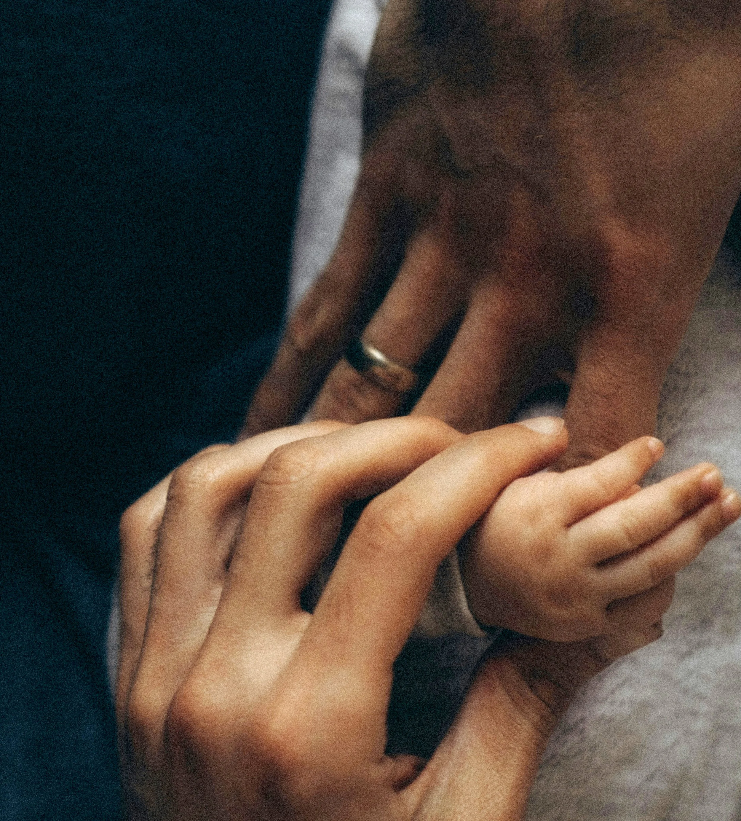 Close-up of two hands with one hand touching the other's back, both wearing rings.