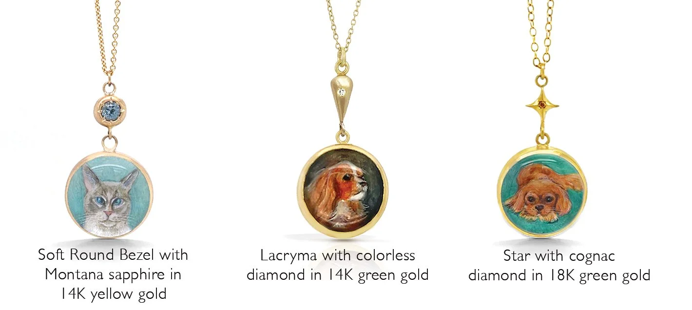 Three gold necklaces with hand-painted charms of a cat, a dog, and a puppy. The cat pendant is in a circular gold frame with a blue background, and has a small diamond. The dog pendant is in a gold frame with a dark background and a small diamond. The puppy pendant is in a gold frame with a green background and a star-shaped design connecting to the chain.