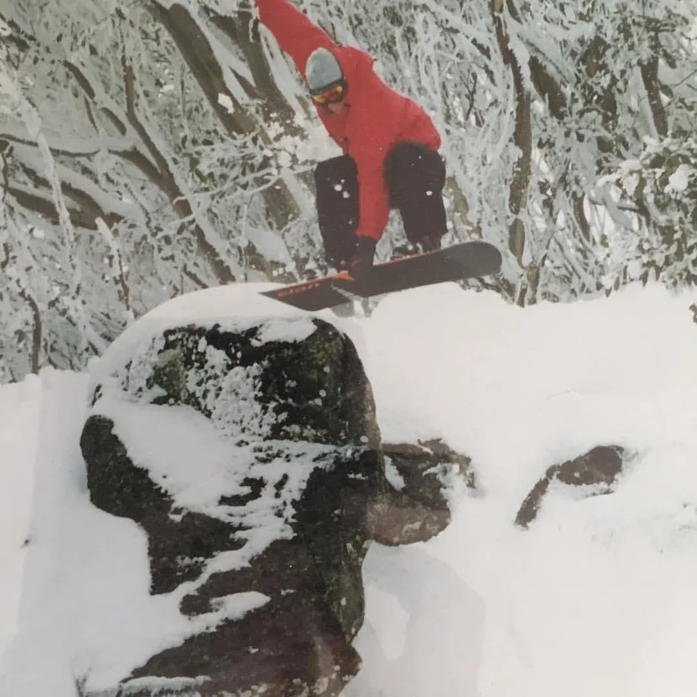 Jarrod Carman snowboarding off a snow-covered rock