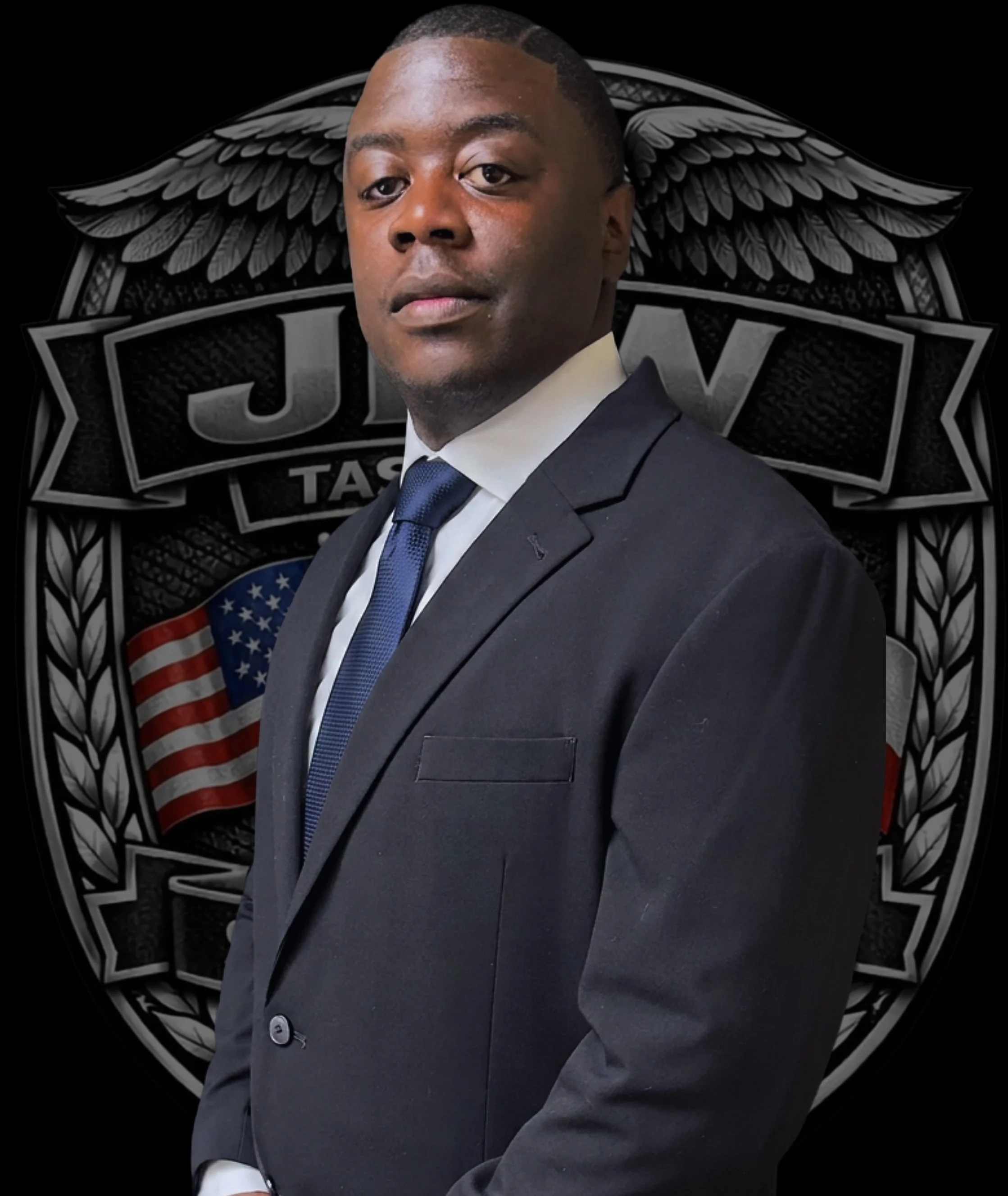 A man in a suit and tie, standing in front of a black background with a logo that includes wings and the American flag.