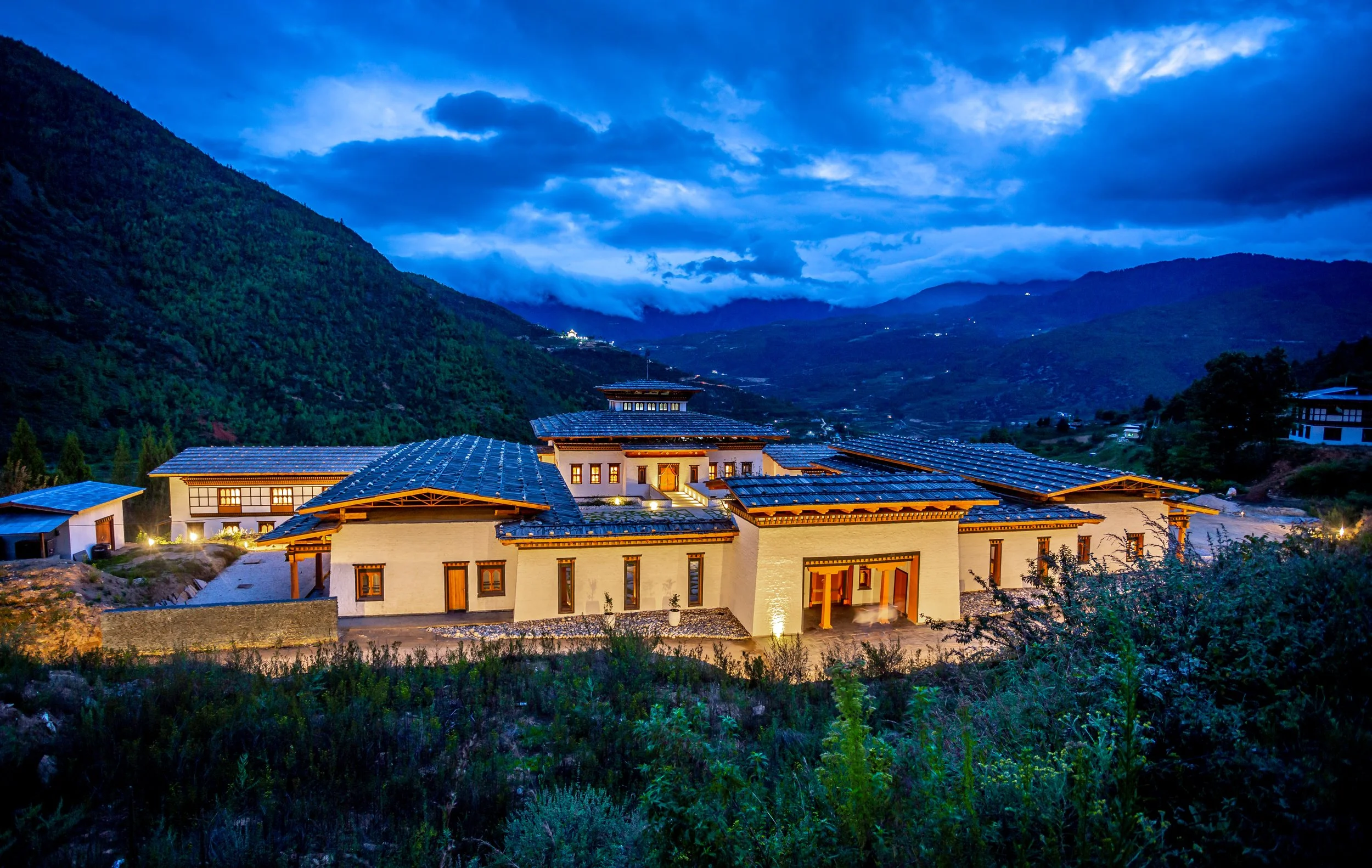 Nighttime view of a mountain village with lit buildings and a cloudy sky.