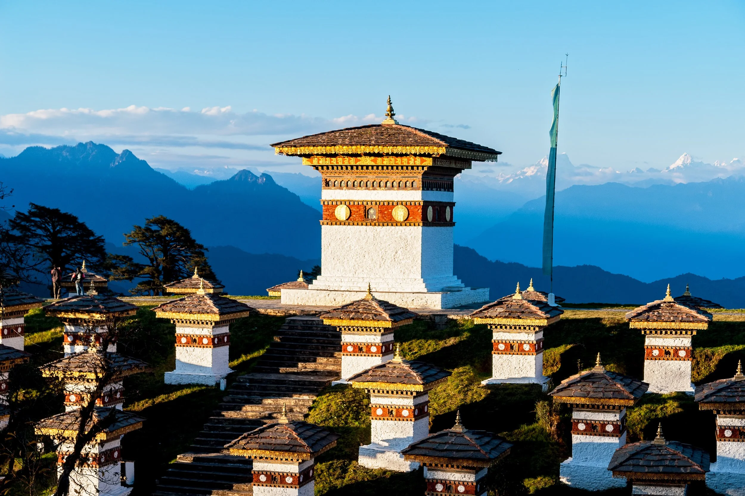 A traditional Bhutanese chorten (stupa) with mountainous landscape in the background.