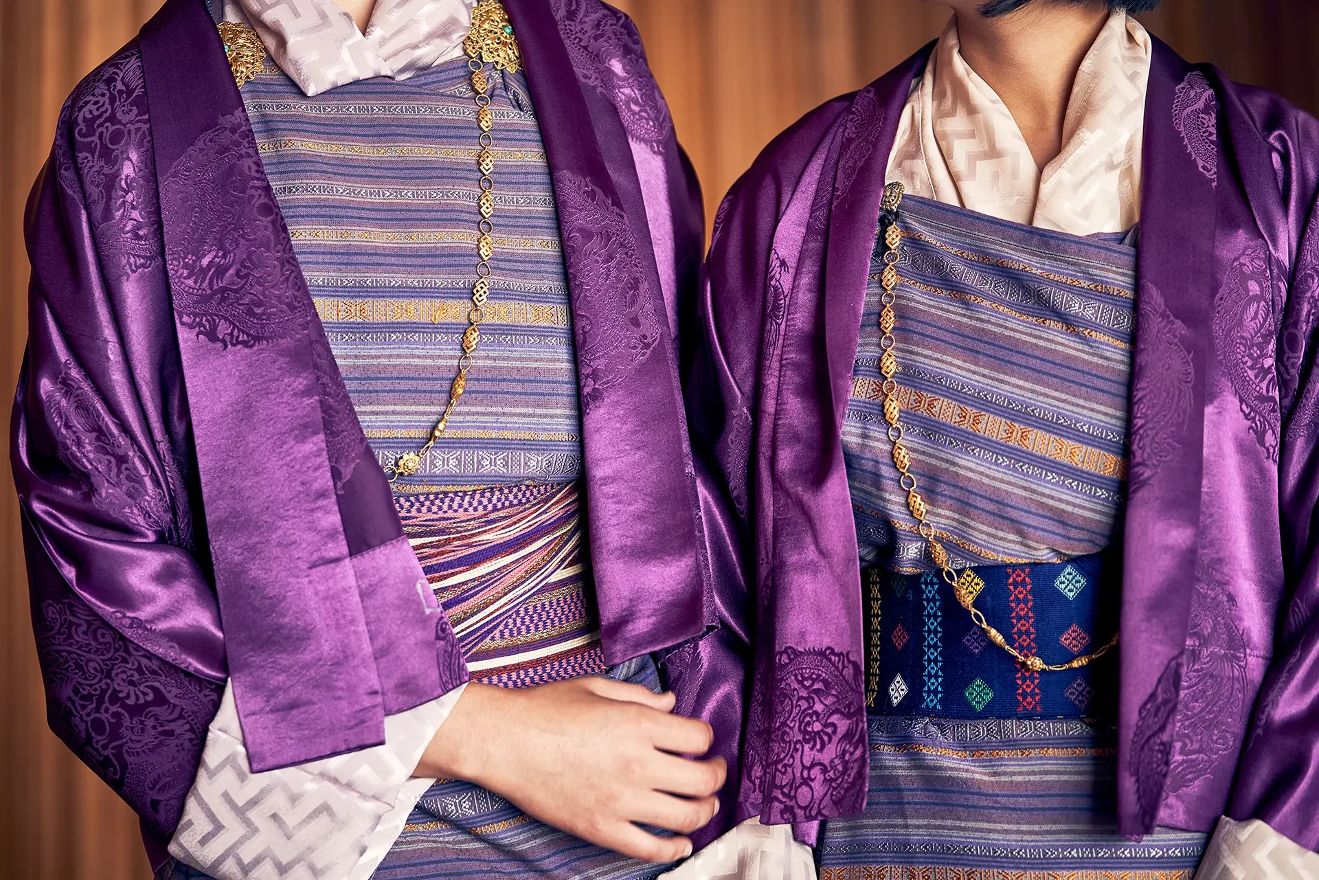 People wearing traditional Thai clothing in purple and blue with intricate patterns and gold accessories.