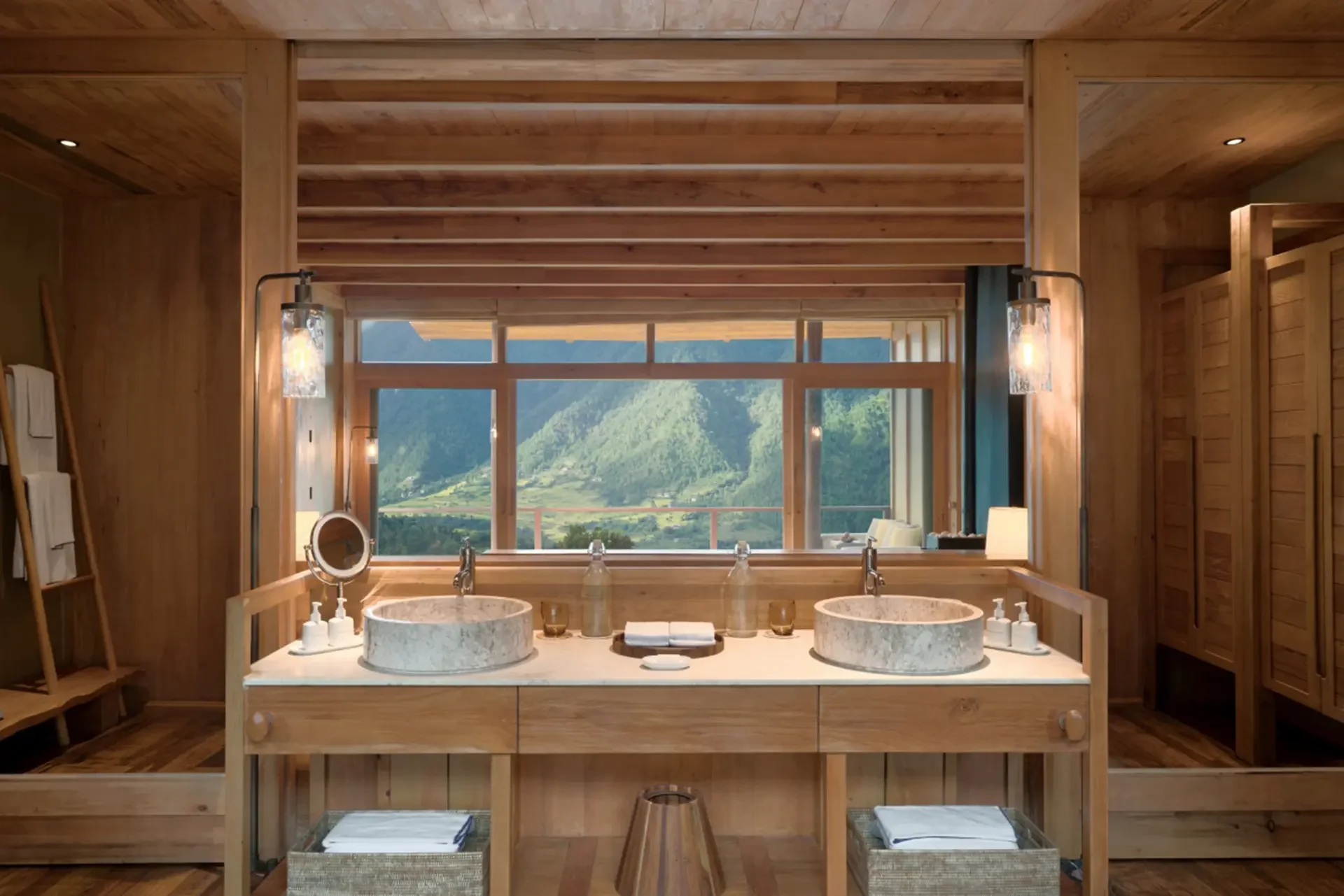 Wooden bathroom with two marble sinks, large window offering mountain view, and warm lighting.