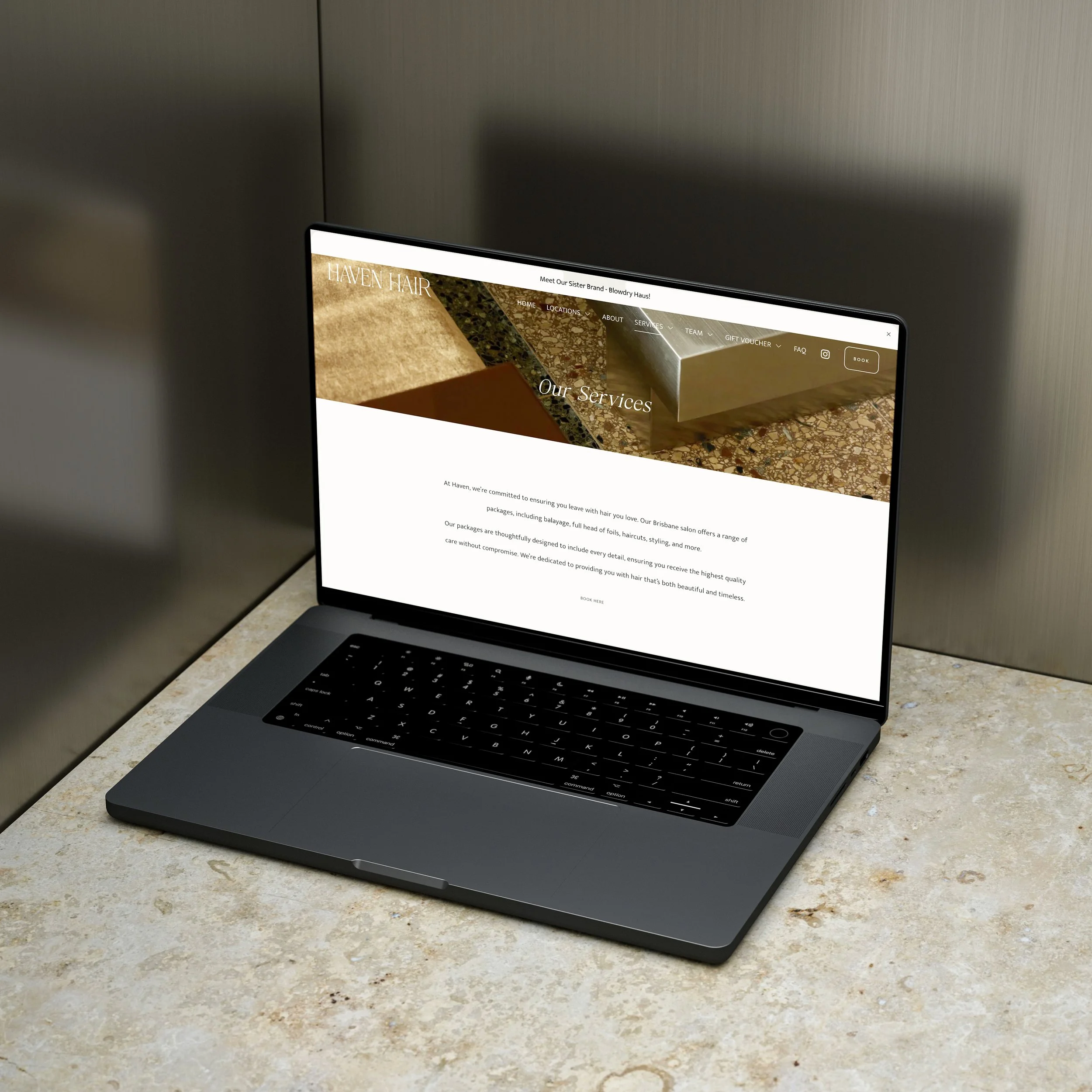 A laptop on a marble table displaying a website for Haven Hair, a hair salon, showing their services page with a header and introductory text.