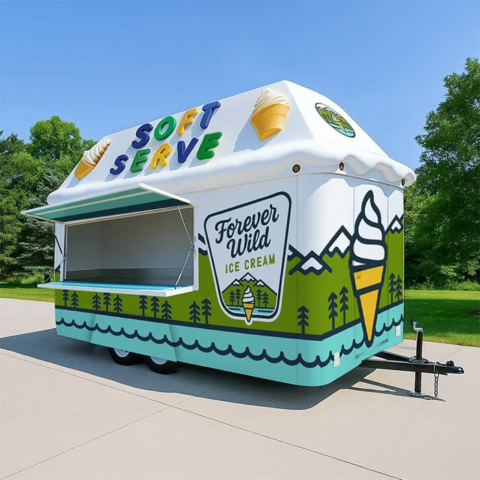 Ice cream trailer with colorful lettering that says 'Soft Serve,' decorated with ice cream cones and mountain scenery, promoting 'Forever Wild Ice Cream'.