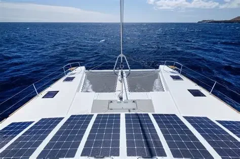 View of a boat deck with solar panels, facing open ocean under a partly cloudy sky.