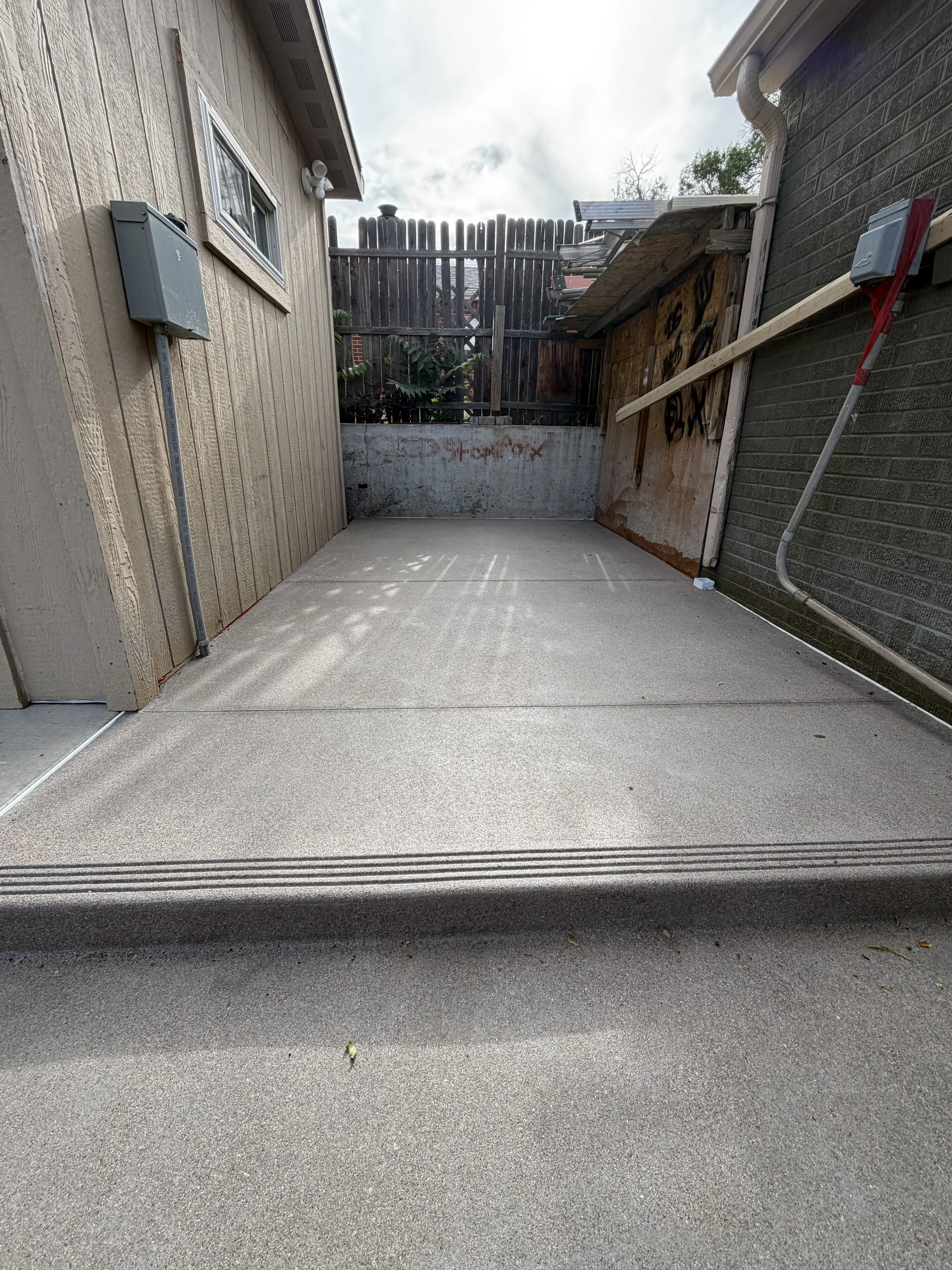 backyard walkway between the house and shed. sandscape concrete finish with freshly cut control joints.
