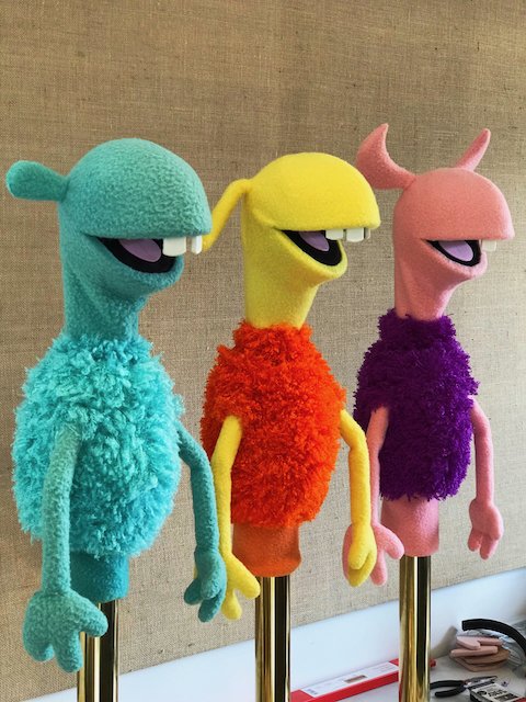 Three colorful puppet characters stand side by side