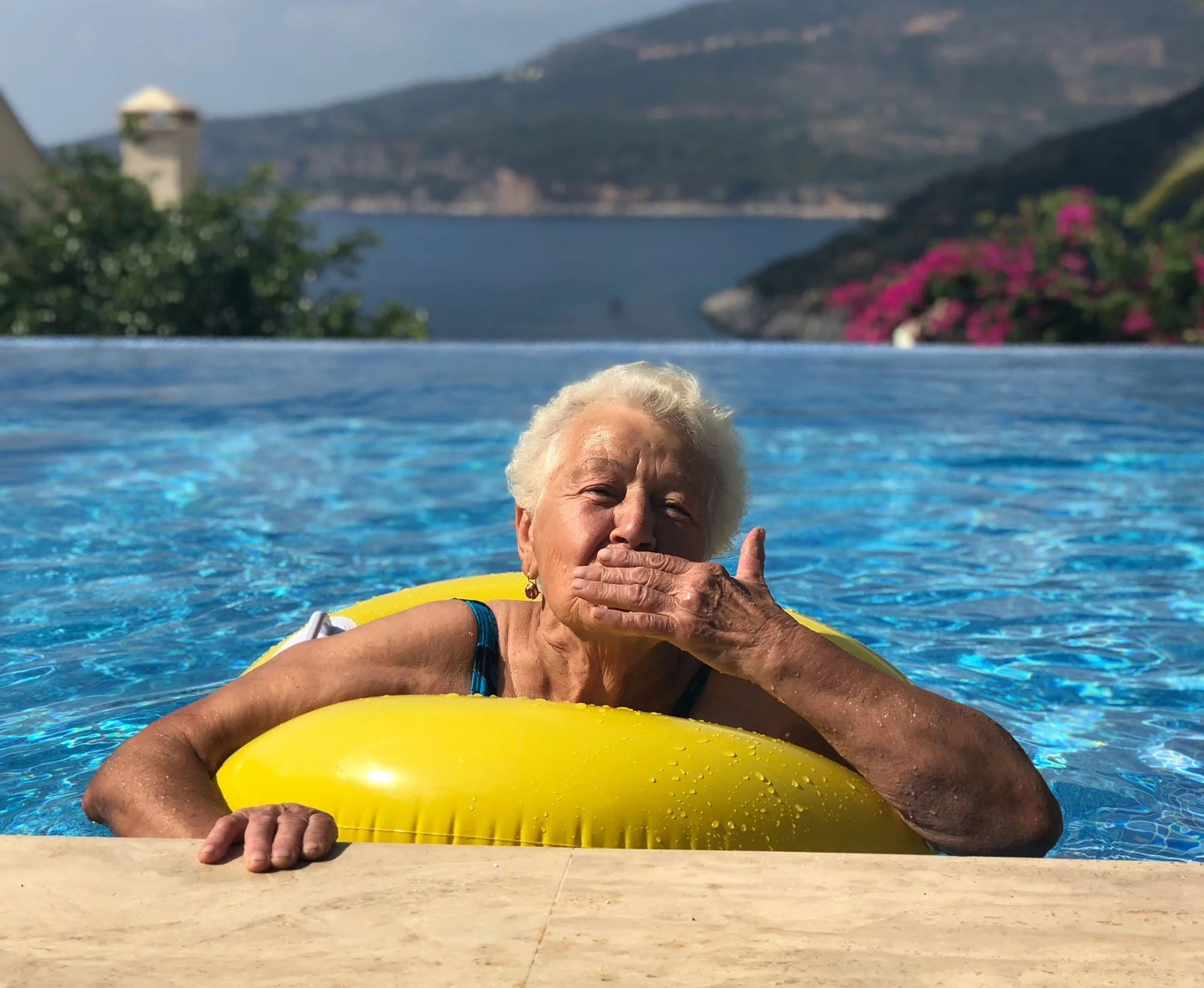 Elderly lady in a swimming pool on an inflatable float for hydrotherapy sessions for low impact water-based physiotherapy