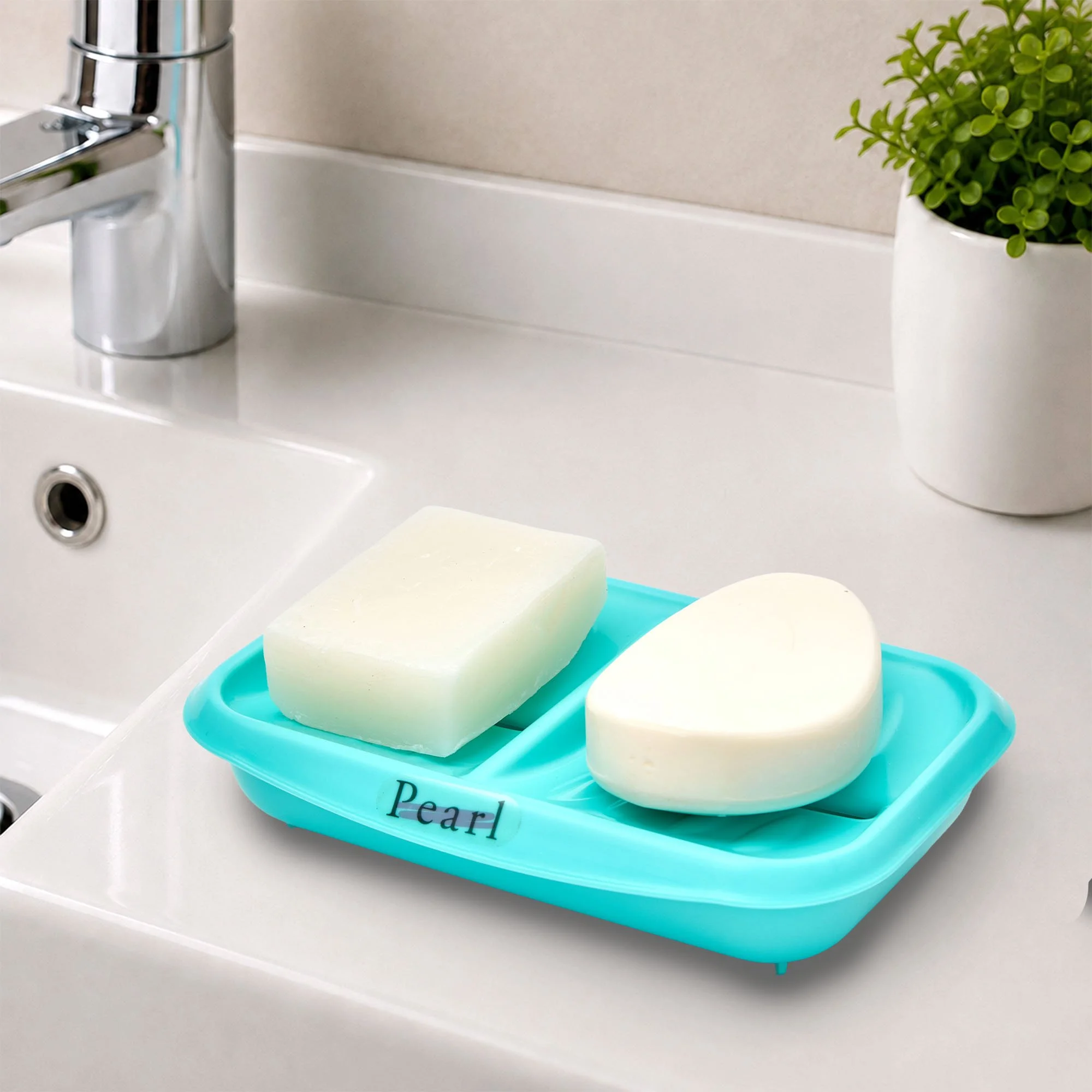 A white ceramic sink with a silver faucet, a potted green plant, and a blue soap dish filled with white soap bars labeled "Pearl."