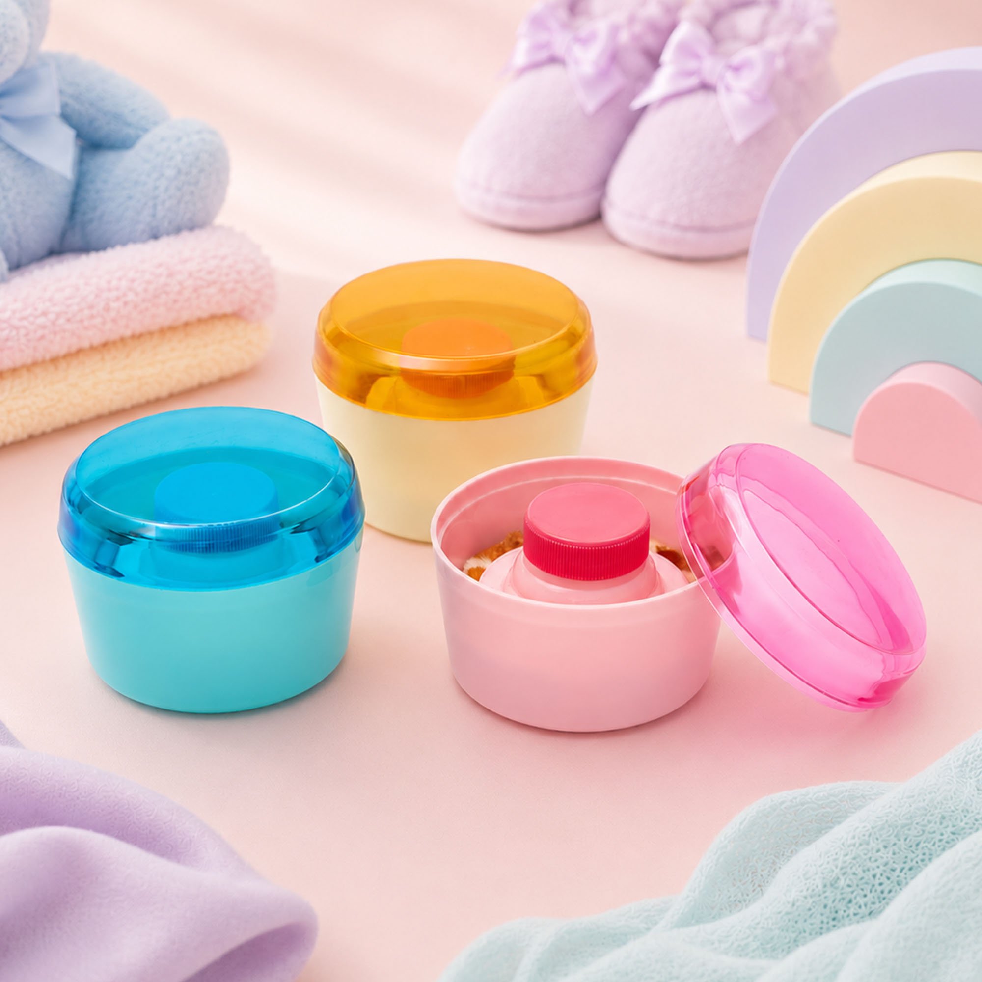 Colorful foam bath bombs and plush slippers arranged on a pastel pink surface.