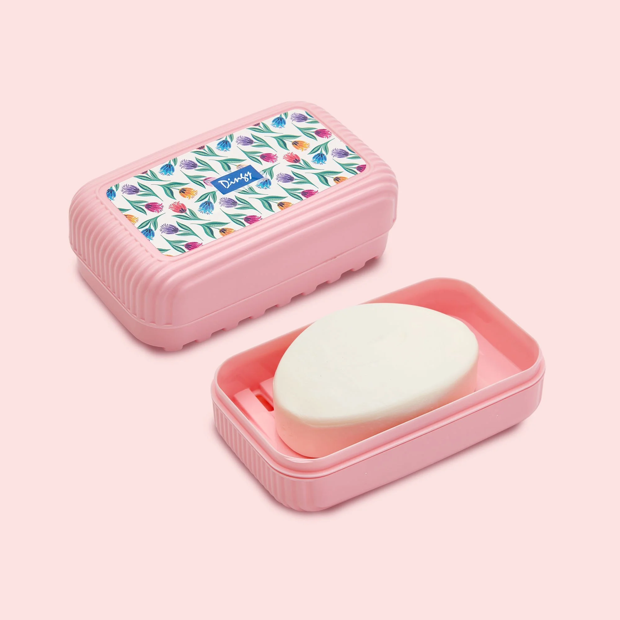 A pink plastic container with a floral pattern and the brand name Dimsy on the lid, containing two white soap bars, placed on a pink background.