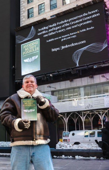 Captured in Times Square, Jim Loveless holds Avoiding Muddy Foxholes, bringing his father’s legacy to life through a moment of pride and global recognition.