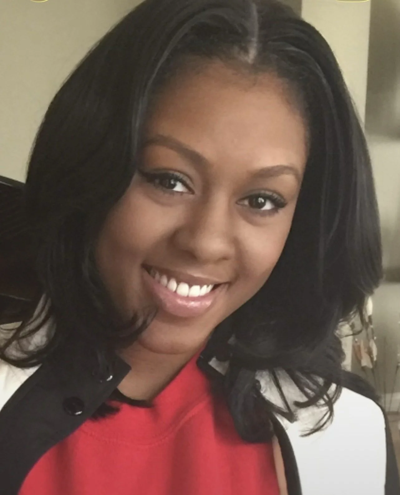 Close-up of a woman with dark hair and a smile, wearing a red and white outfit.