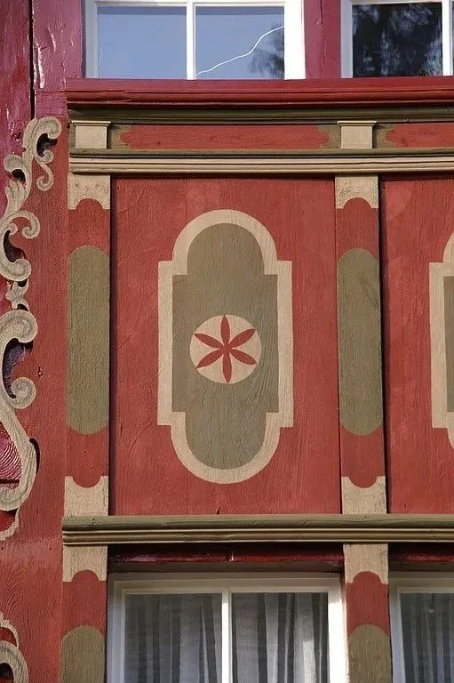 Traditionell verzierte Fassade mit rotem und grünem Dekor, Fenster und ornamentalem Holzdekor
