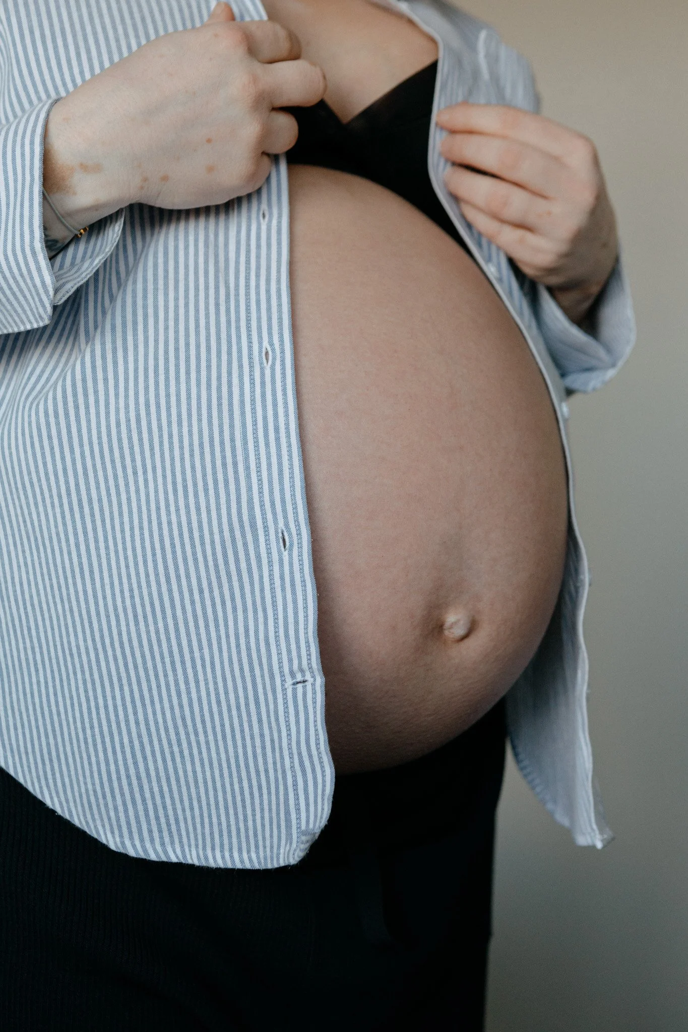 familt-portraiture-pregnant-belly-buttoning-shirt.jpg