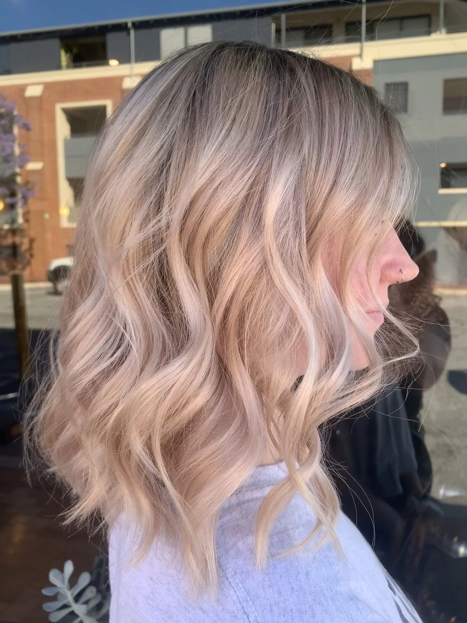 Side profile of a woman with shoulder-length blonde hair styled in loose waves