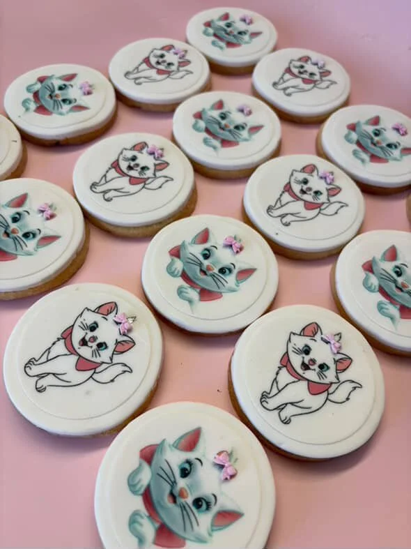 Decorative cookies with cartoon kitten illustrations on a pink background.