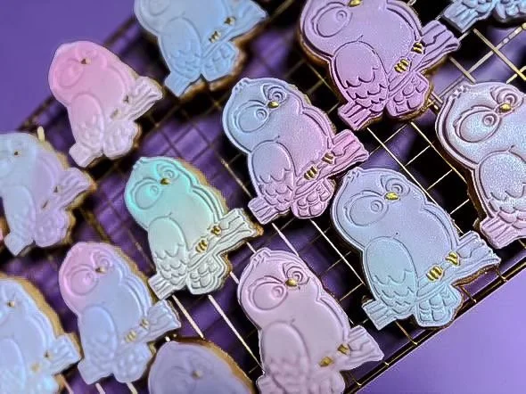 Colorful pastel-colored bunny-shaped cookies with gold accents, arranged on a wire rack.