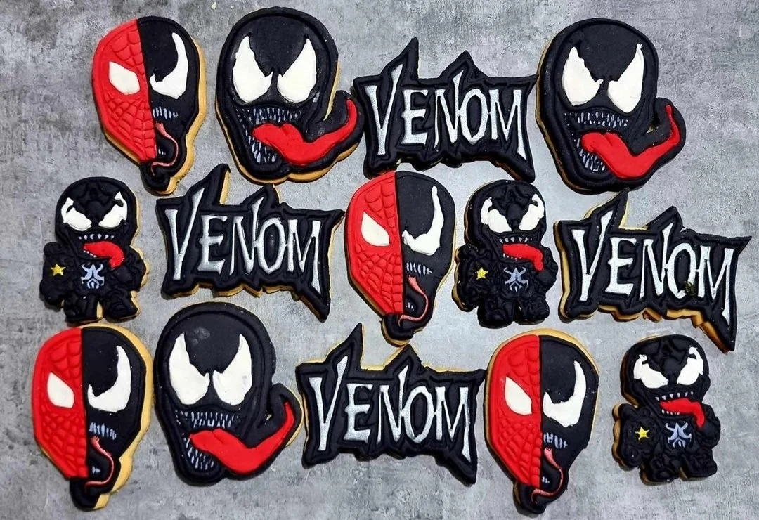 Decorative cookies shaped like Venom and Spider-Man characters from Marvel Comics, with some cookies displaying the Venom logo.