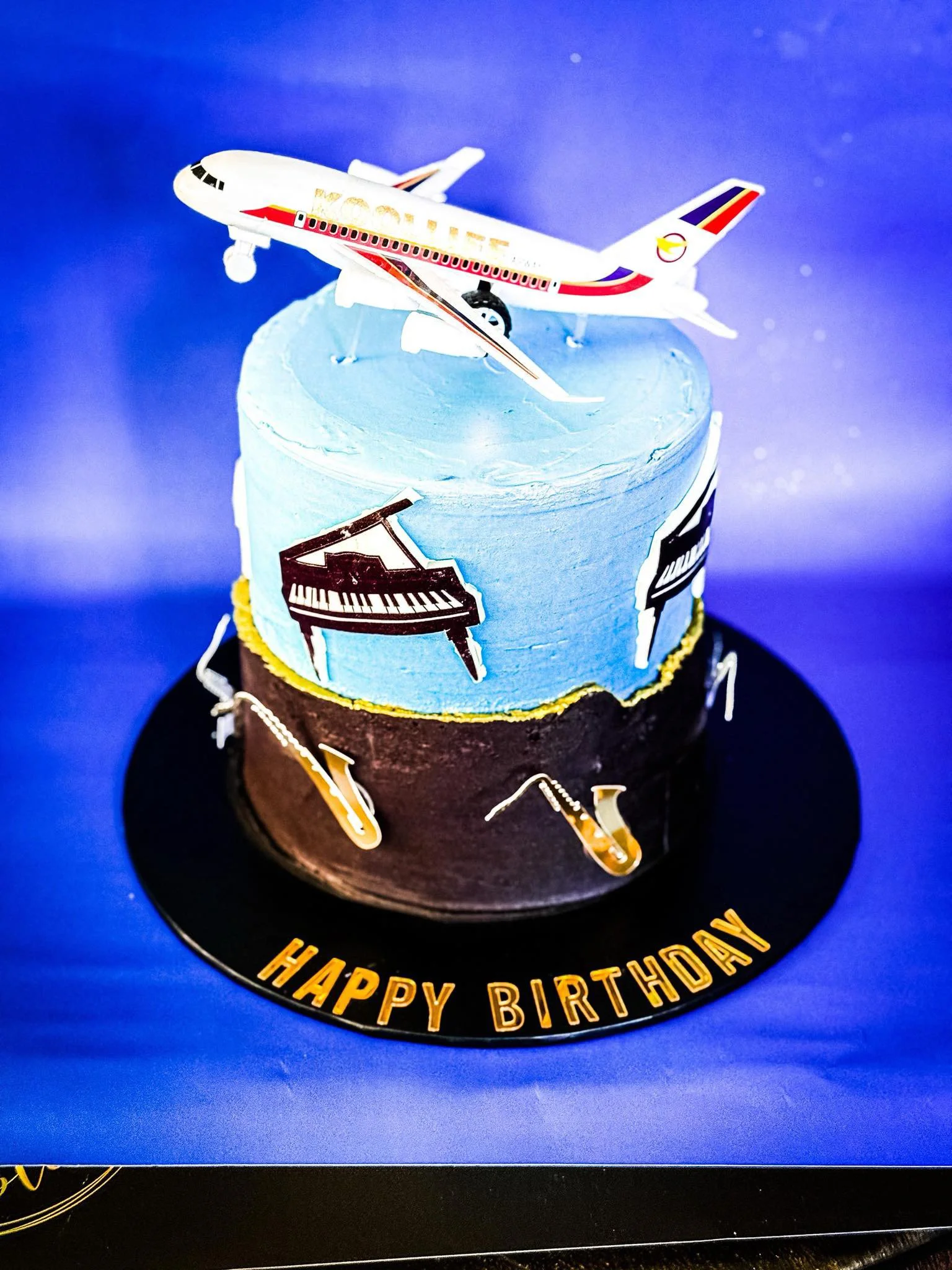 A birthday cake decorated with a box of an airplane toy on top, with 
