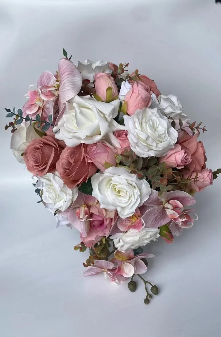 A bouquet of pink and white flowers including roses, orchids, and greenery.
