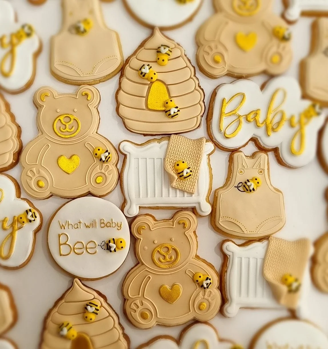 Cookies decorated with baby and bee themes, including teddy bear, beehive, baby bottles, and the words 'Baby' and 'What will Baby Bee' with small bee decorations.