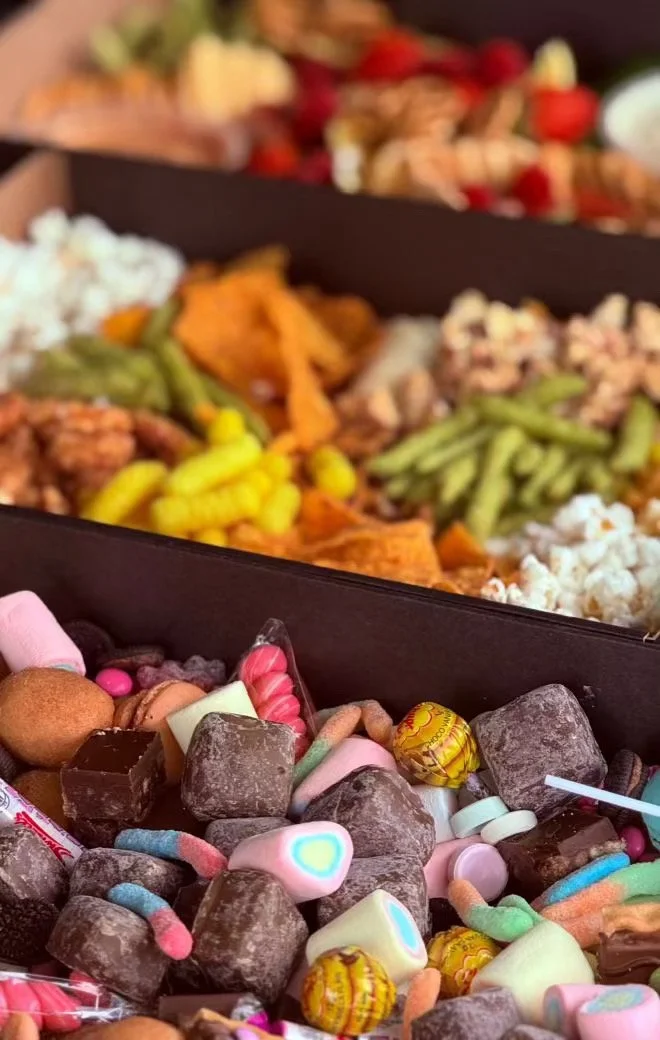 Assorted Halloween candies, including chocolates, marshmallows, lollipops, and gummies, with blurred background of various colorful foods.