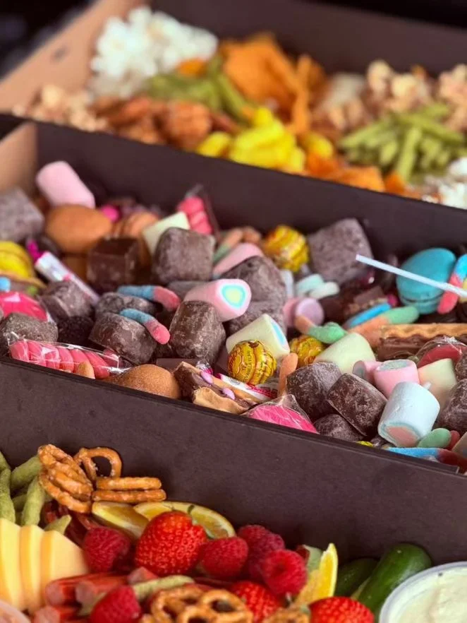 Assorted candies in a box with strawberries and vegetables in the foreground